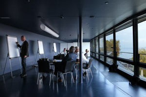 Workshopteilnehmer:innen sitzen an schwarzen Tischen in der Blauen Lounge im Festspielhaus Bregenz