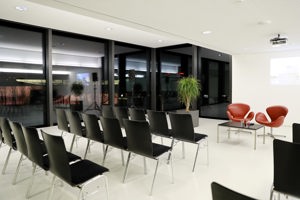 Schwarze Stuhlreihen und kleines Podium mit roten Ledersessel im weißen Saal Panorama im Festspielhaus Bregenz