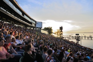 Vollbesetzte Seetribüne bei Sonnenuntergang
