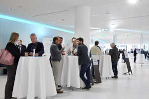 Kongressteilnehmer:innen im Foyer an Stehtischen mit weißen Tischtüchern im Festspielhaus Bregenz