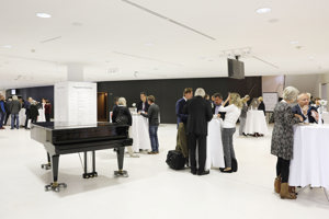 Kongressteilnehmer:innen im Foyer an Stehtischen und ein Konzertflügel im Festspielhaus Bregenz