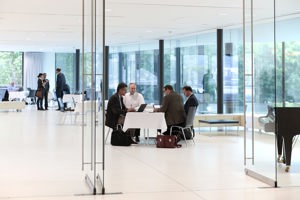 Symposiums-Teilnehmer:innen an eckigen Tischen im Parkstudio des Festspielhauses Bregenz