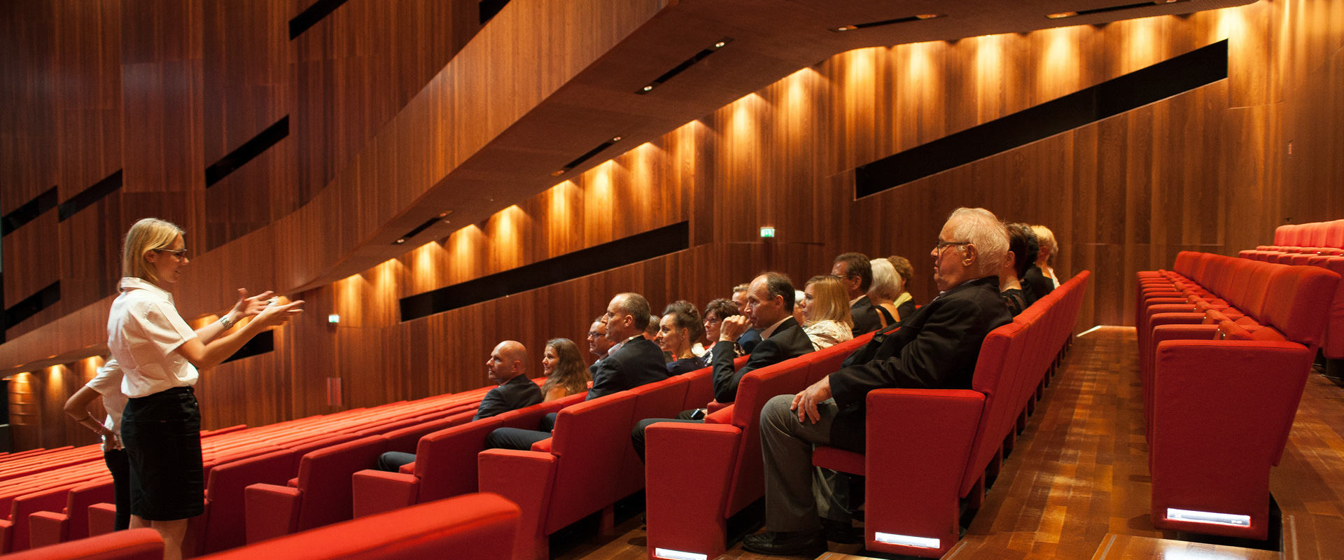 Ein Guide gestikuliert vor den im Großen Saal des Festspielhauses Bregenz sitzenden Führungsteilnehmer:innen © pi grafik, Bregenzer Festspiele