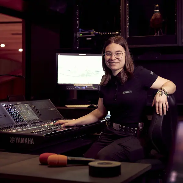 Veranstaltungstechnik-Lehrling Fiona sitzt vor einem Mischpult und einem Screen © Anja Koehler