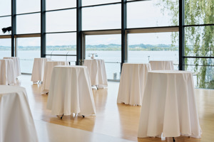 Stehtische mit weißen Tischdecken im Seefoyer des Festspielhauses Bregenz mit Blick auf den Bodensee und das deutsche Ufer