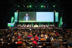 Tagungsteilnehmer:innen sitzen vor einer großen Bühne mit Leinwand in der Werkstattbühne des Festspielhauses Bregenz