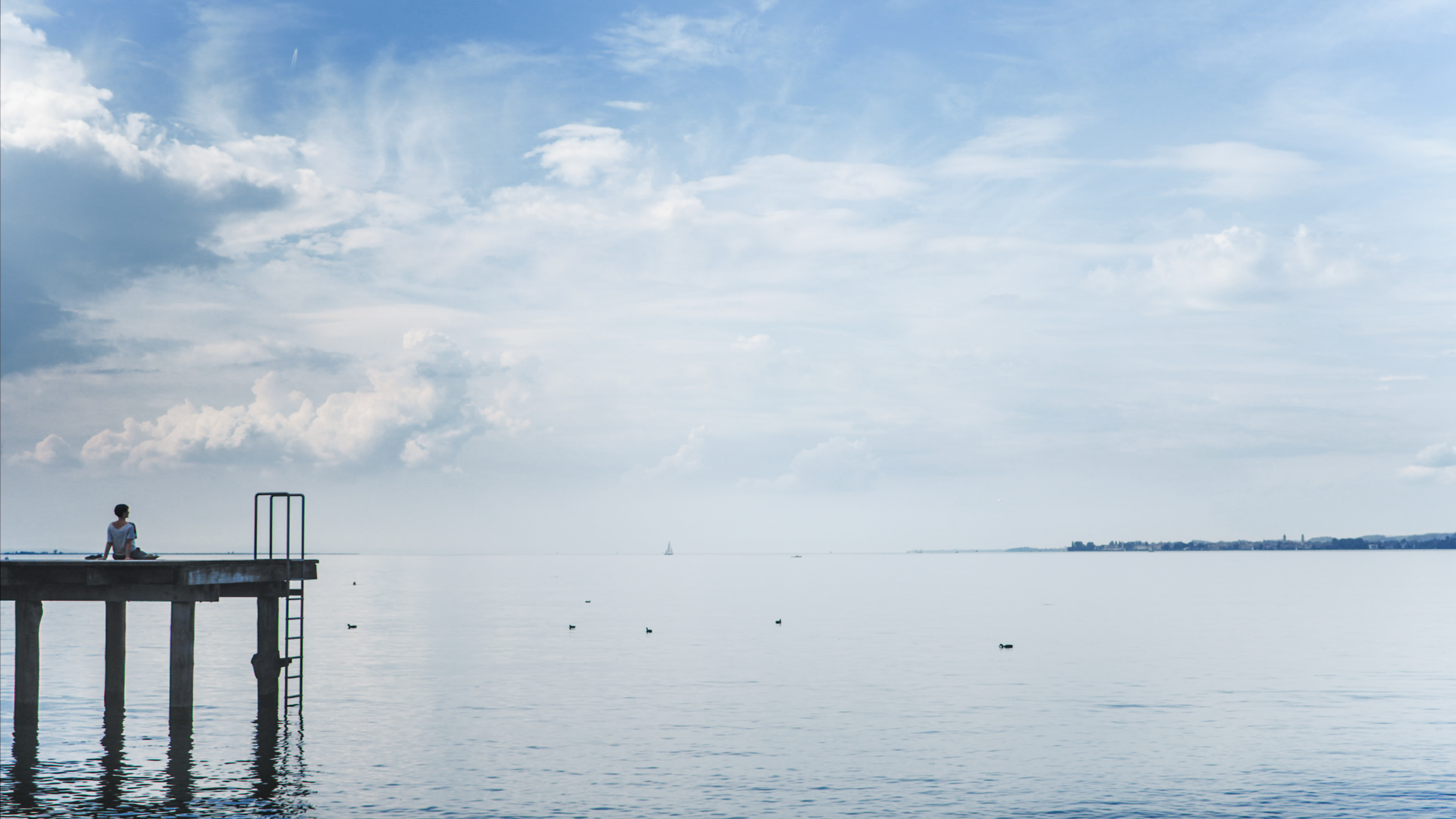 Eine Frau sitzt auf einem Steg und Blick über den Bodensee © Philipp Moosbrugger