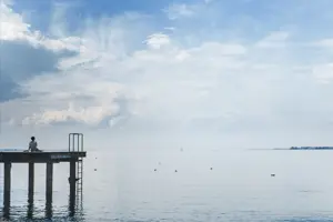 © Philipp Moosbrugger Eine Frau sitzt auf einem Steg und Blick über den Bodensee © Philipp Moosbrugger